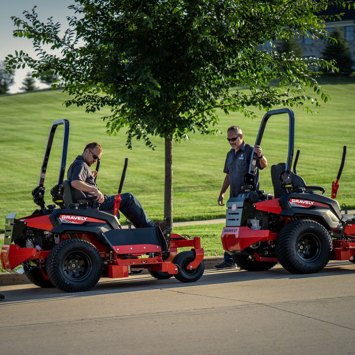 A couple of men riding on the back of red lawn mowers Game Arcade